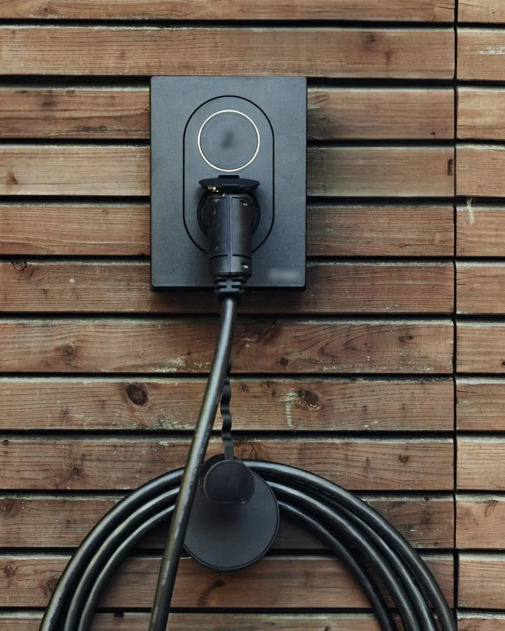Elbillader med ladekabel på en trevegg